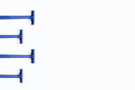 Four blue plastic razors are located on a white background. Disposable blue plastic razors lie on a white background with free space for text or advertising. Shaving and smooth skin careの写真素材