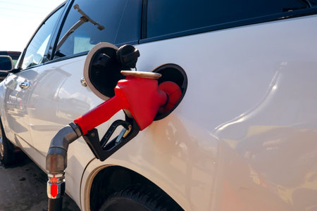 Filling a car with fuel at a gas station. The car fills up with gasoline at a gas station. gas...