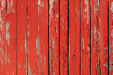 Background of old wooden boards painted with red cracked paint. Old fence or building wall made of wood with peeling red paint. Free space for text. Building in need of repair or abandoned areaの写真素材