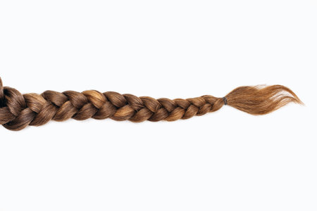 Female hair in the form of a braid on a white isolated background. Red hair braided close-up. Beautiful healthy natural female hair without dyeingの写真素材