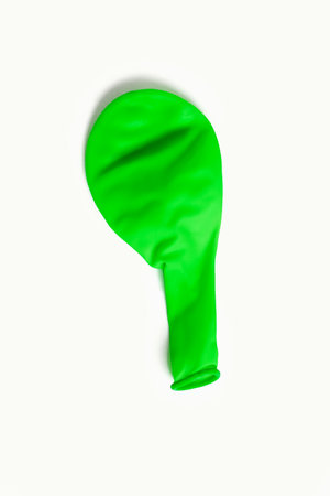 Green air deflated balloon on a white background. One uninflated top view balloon. The concept of preparing for the holiday in the form of decorations with balloonsの写真素材