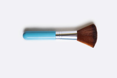 Cosmetic brush for make-up on a white background. One blue makeup brush on an isolated white background. Top view trendy female cosmetic tool in the form of a soft brushの写真素材
