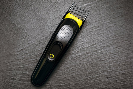 Razor trimmer for cutting hair lies on a black rough background. Electric razor for barbershop....