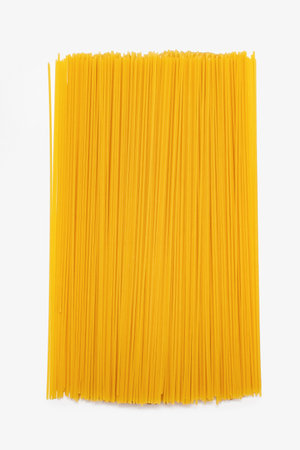 Long raw spaghetti on a white isolated background. Italian cuisine made from durum wheat in the form of spaghetti. Yellow spaghetti close-up on a vertical white backgroundの写真素材