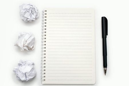 Blank open notepad, pen and crumpled paper wads on white background. Free space for text. Top view of a blank open notepad. Education or business concept. Work related to the creation of textの写真素材
