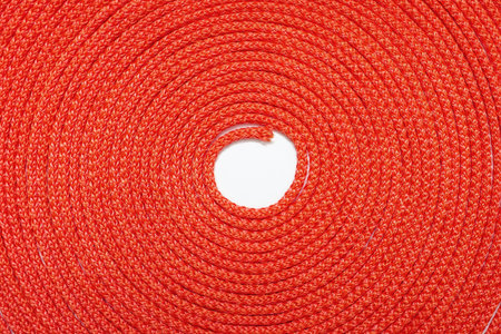 Background of red rope twisted in a circle. Texture of red nylon rope close up. Free space for text and advertising. Roll of red rope as a beautiful backgroundの写真素材