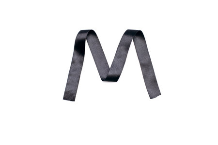 Satin black ribbon in the shape of the letter m on a white isolated background. Narrow textile black ribbon folded in the shape of the letter mの写真素材
