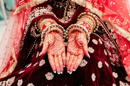 The hands of the Indian bride are adorned with curly red patterns and jewelry made from bracelets and rings. Beautiful drawings in the Indian style of henna on the palms of the brideの写真素材