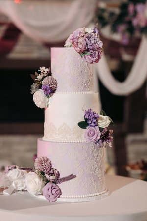 A beautiful tiered cake decorated with flowers at a wedding party. Delicious chic wedding cake in a restaurant for guests of the bride and groomの写真素材