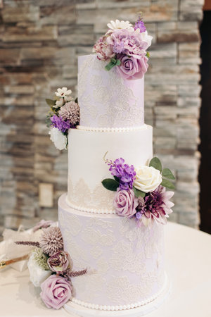 A beautiful tiered cake decorated with flowers at a wedding party. Delicious chic wedding cake in the restaurant for the guests of the bride and groom. Traditional wedding cakeの写真素材