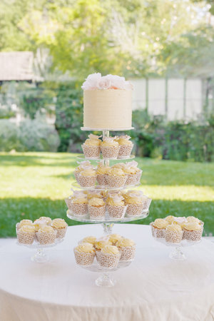 Festive wedding cake decorated with roses and cupcakes with cream. A table with desserts at a banquet. Many cupcakes with creamy vanilla cream and birthday cake on a three-tiered plateの写真素材