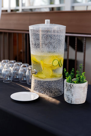 Cool refreshing lemonade in a jug close-up. A cold drink with bubbles and slices of lemon stands outdoors. Fresh cold lemonade in a glass siphon and empty glasses for a treat. Summer refreshing drinkの写真素材