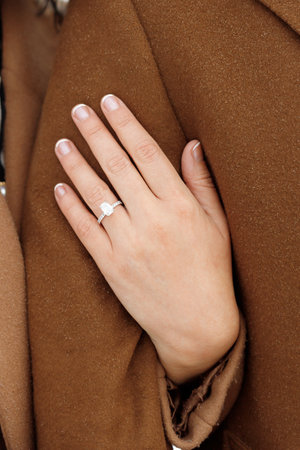 Woman's hand with engagement ring together with men as a symbol of unity, trust and love. Elegant wedding ring with gemstones on fingerの写真素材