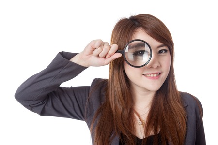 Asian businesswoman look through magnifying glass and smile isolated on whtie backgroundの写真素材