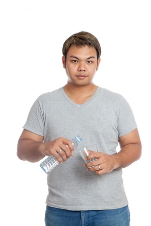 Asian strong man pour water into a glass look at the camera isolated on white backgroundの写真素材