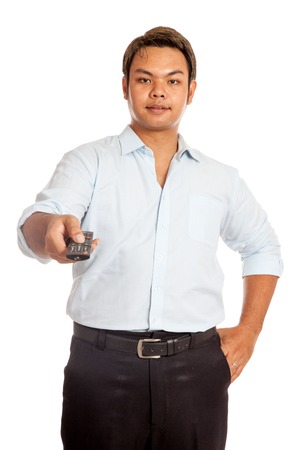 Asian man point a remote control to camera isolatedの写真素材