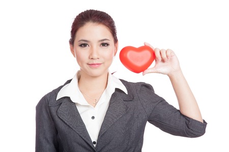 Asian businesswoman show red heart next to her face isolated on white backgroundの写真素材