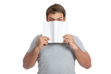 Asian man close his mouth with a book look at camera isolated on white backgroundの写真素材