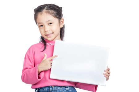 Asian little girl point to a blank sign and smile isolated on white backgroundの写真素材