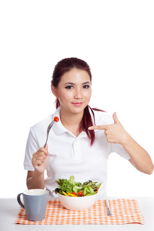 Asian girl eat salad with pointing hand sign isolated on white backgroundの写真素材