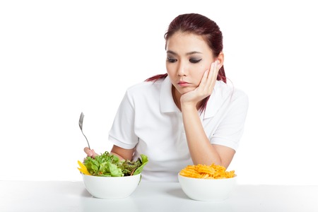 Asian girl fed up with crisps and salad isolated on white backgroundの写真素材