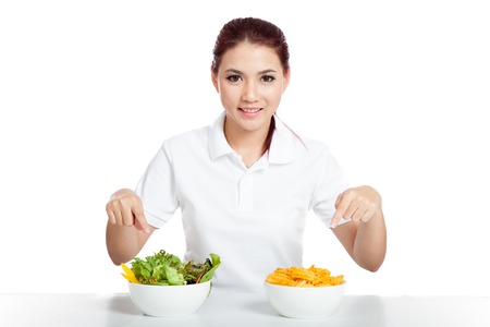 Asian girl point to salad and crisps bowls and smile  isolated on white backgroundの写真素材