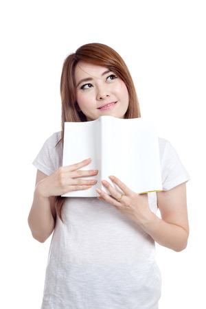 Asian girl imagine and smile with a book isolated on white backgroundの写真素材