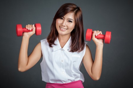 Asian girl hold red dumbbell with both hand on gray backgroundの写真素材