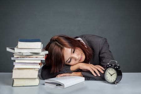 Asian businesswoman get tired reading many books on gray backgroundの写真素材
