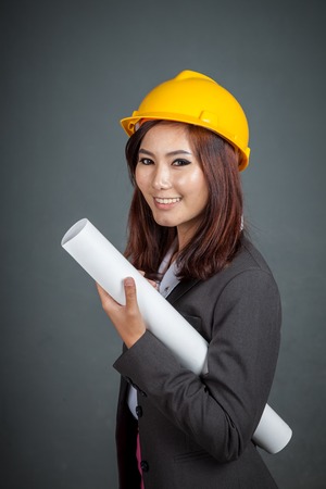 Asian engineer girl hold a blueprint and smile on gray backgroundの写真素材