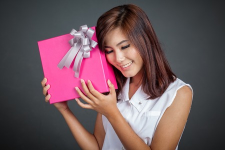 Beautiful Asian girl love a gift box on gray backgroundの写真素材