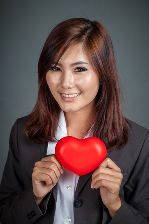 Close up Asian businesswoman with red heart on gray backgroundの写真素材