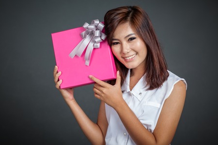 Beautiful Asian girl happy with a gift box on gray backgroundの写真素材
