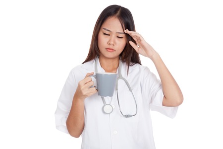 Asian young female doctor got headache with a cup of coffee  isolated on white backgroundの写真素材