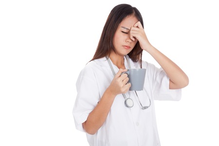 Asian young female doctor got headache with a cup of coffee  isolated on white backgroundの写真素材