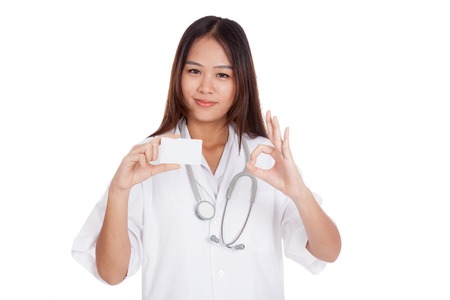 Asian young female doctor show Ok sign with blank card  isolated on white backgroundの写真素材