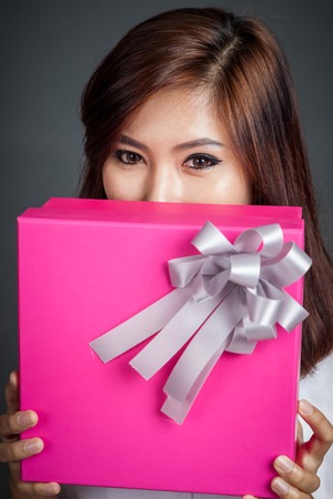 Close up beautiful Asian girl with a gift box on gray backgroundの写真素材
