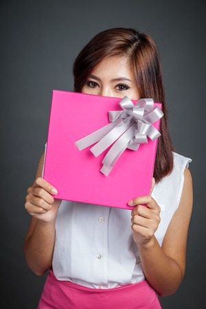 Beautiful Asian girl hold a gift box close her lower face on gray backgroundの写真素材