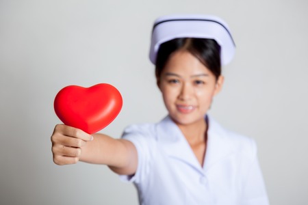 Young Asian nurse show red heart focus at the heart on gray backgroundの写真素材