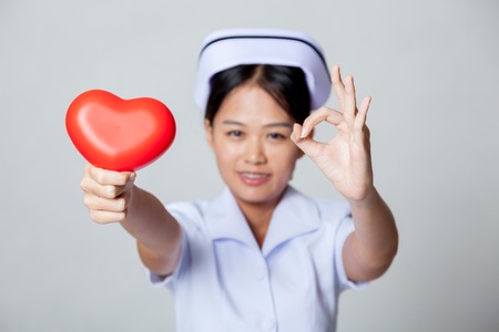 Young Asian nurse OK with red heart on gray backgroundの写真素材