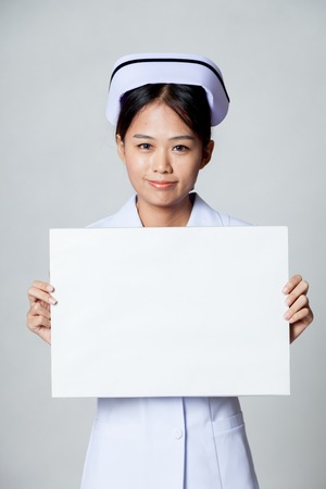 Young Asian nurse show blank sign on gray backgroundの写真素材