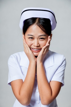 Portrait of  very happy young Asian nurse on gray backgroundの写真素材