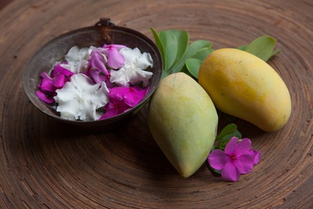Yellow Mangoes on wood table in a spa with flower potの写真素材