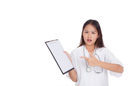 Asian young female doctor upset  point to blank clipboard  isolated on white backgroundの写真素材