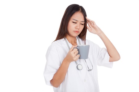 Asian young female doctor got headache with a cup of coffee  isolated on white backgroundの写真素材