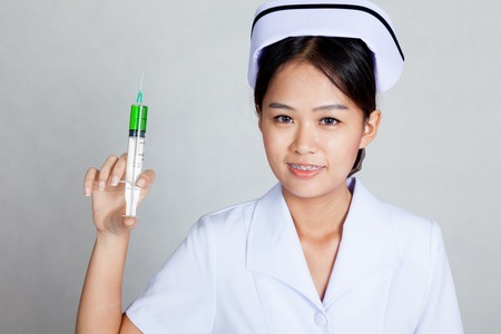 Asian young nurse smile with syringe on gray backgroundの写真素材