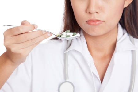 Young Asian female doctor with spoon full with  medicine on white backgroundの写真素材