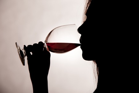 Close up silhouette shot of a female drinking red wine.の写真素材