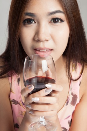 Close up of  beautiful Asian woman hold glass of  red wine on gray の写真素材