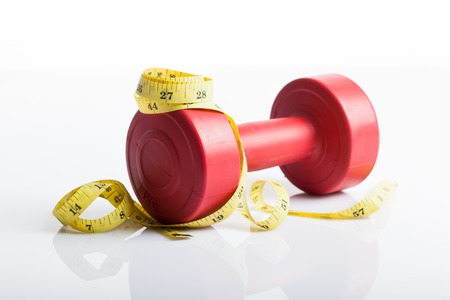 Red dumbbells weight with measuring tape for diet concept on white backgroundの写真素材